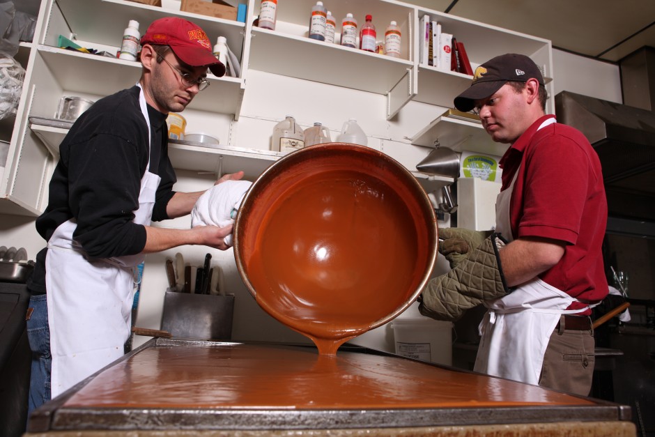 Grant Schultz, right, and his brother pour caramel onto the marble slab to cool overnight.